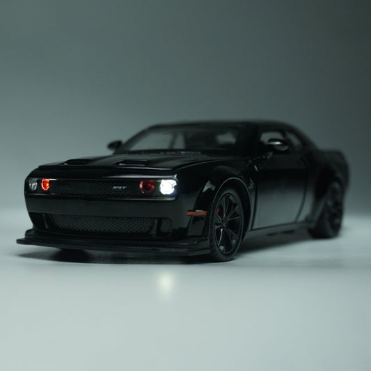 A black die-cast model car resembling a Dodge Challenger SRT, shown from a three-quarter front angle on a neutral gray studio background.